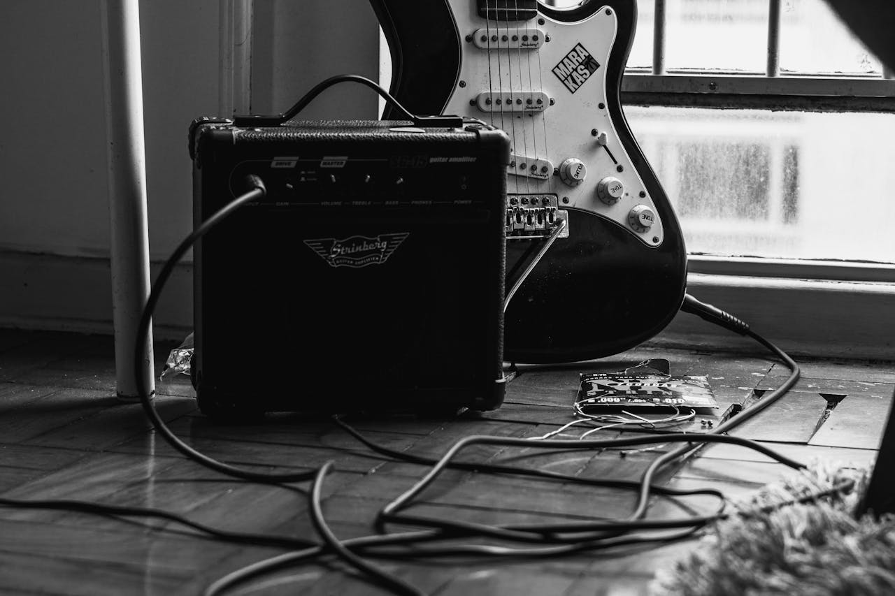 Mastering the First Impression: Your intriguing post title goes here Monochrome image of an electric guitar with an amplifier indoors.